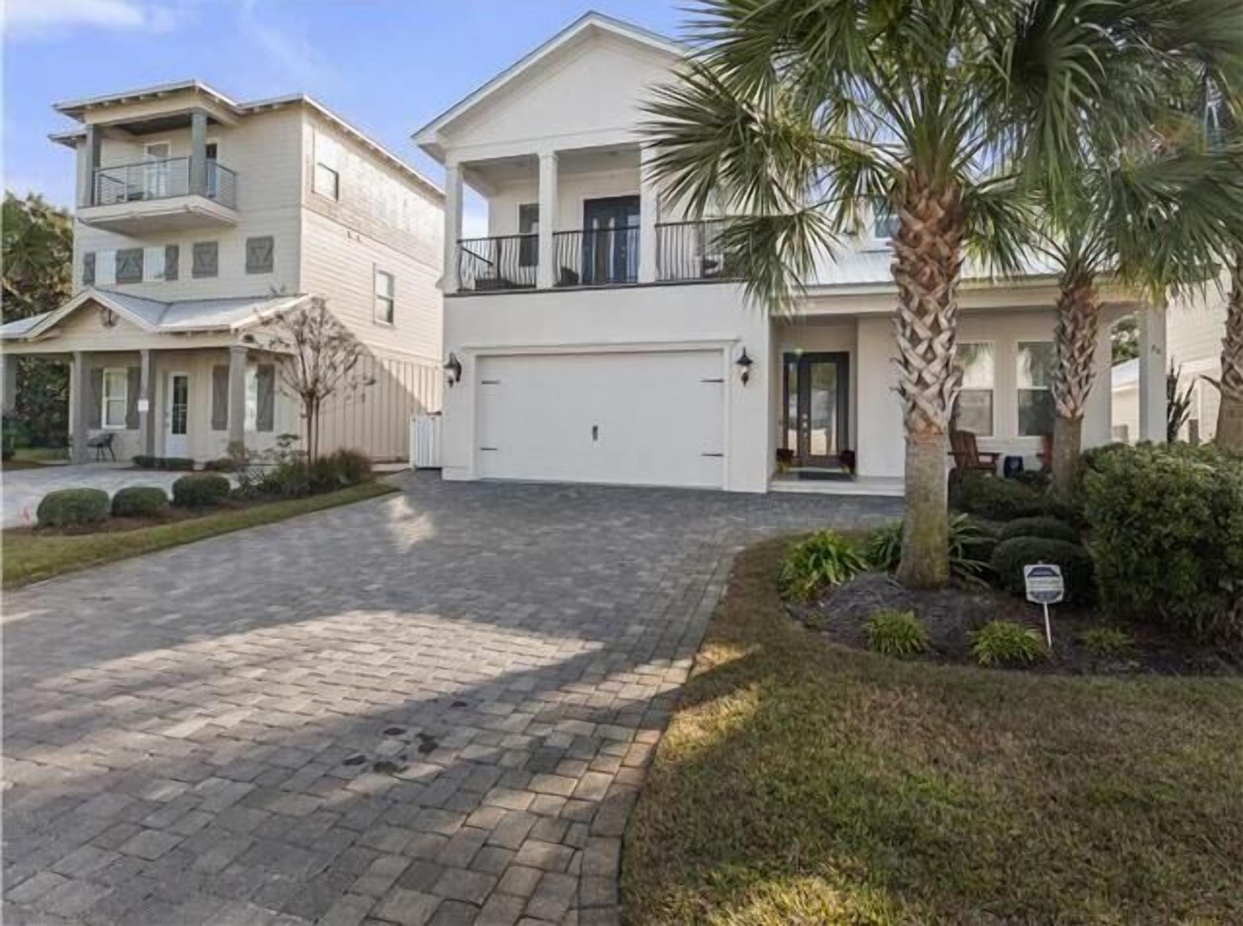 A two-story residential building with a garage, a covered porch, and a landscaped driveway.