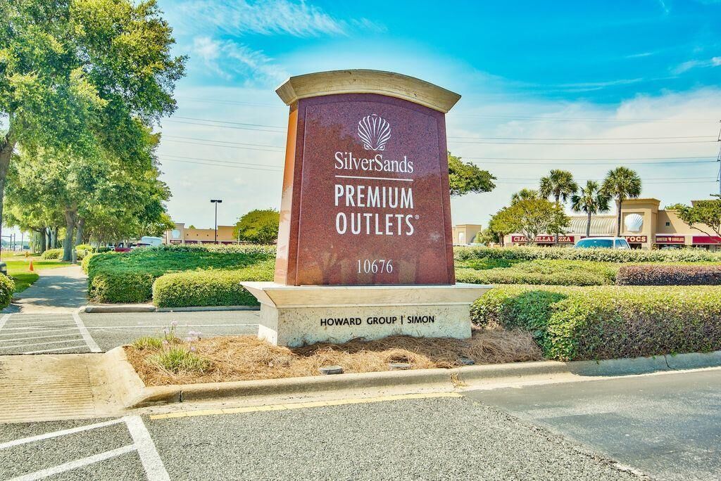 A sign for SilverSands Premium Outlets with a clear sky and parking lot in the foreground.