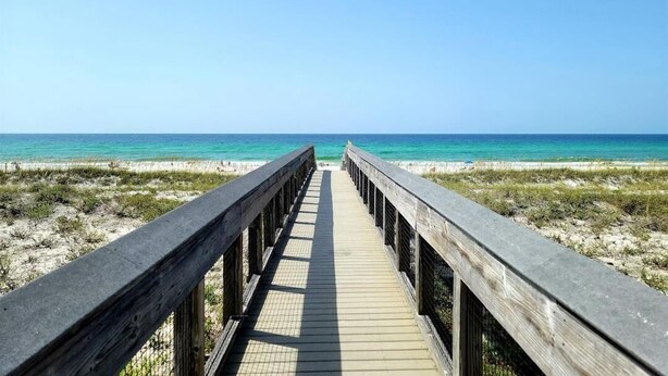 A wooden boardwalk leading to a beach with clear skies. - Tradewinds Condominium #25 (Miramar Beach)