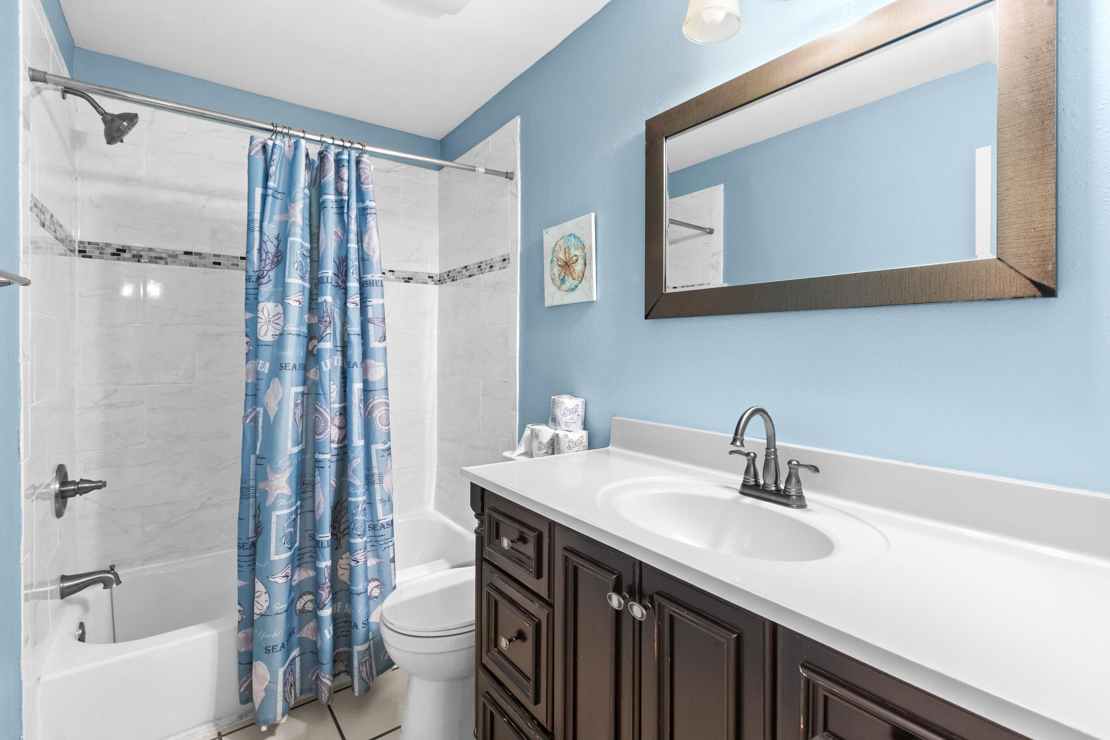 A bathroom with a shower, toilet, bathtub, and a sink with a mirror.