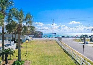 A coastal road with a white fence, palm trees, and a clear view of the ocean. - Tradewinds Condominium #2 (Miramar Beach)