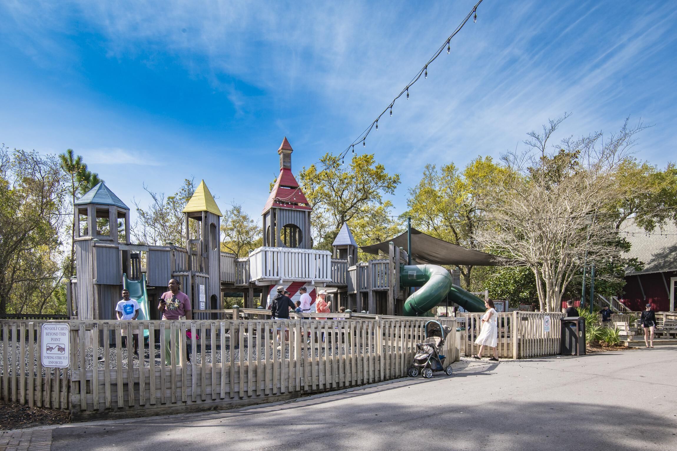 A wooden play structure with multiple towers and a slide.