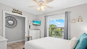 A bedroom with a bed, a ceiling fan, a TV, a window with curtains, and a view of the outdoors. - Summerspell 306 (Miramar Beach)