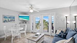 A living room with a white dining set, a coffee table, a blue sofa, and a ceiling fan. - Summerspell 306 (Miramar Beach)