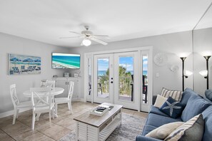 A living room with a white dining set, a coffee table, a blue sofa, and a ceiling fan. - Summerspell 306 (Miramar Beach)