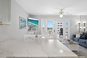 A modern living room with a white marble table, a blue sofa, and a ceiling fan. - Summerspell 306 (Miramar Beach)
