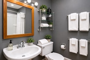 Ein Badezimmer mit Waschbecken, Toilette und Spiegel, mit Handtüchern und Pflanzen auf Regalen.