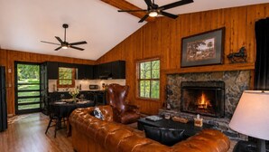 Ein gemütliches Wohnzimmer mit Ledersofa, Kamin und Essbereich mit Tisch und Stühlen.