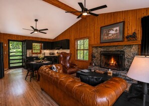 Ein gemütliches Wohnzimmer mit Ledersofa, Kamin und Essbereich mit Tisch und Stühlen.