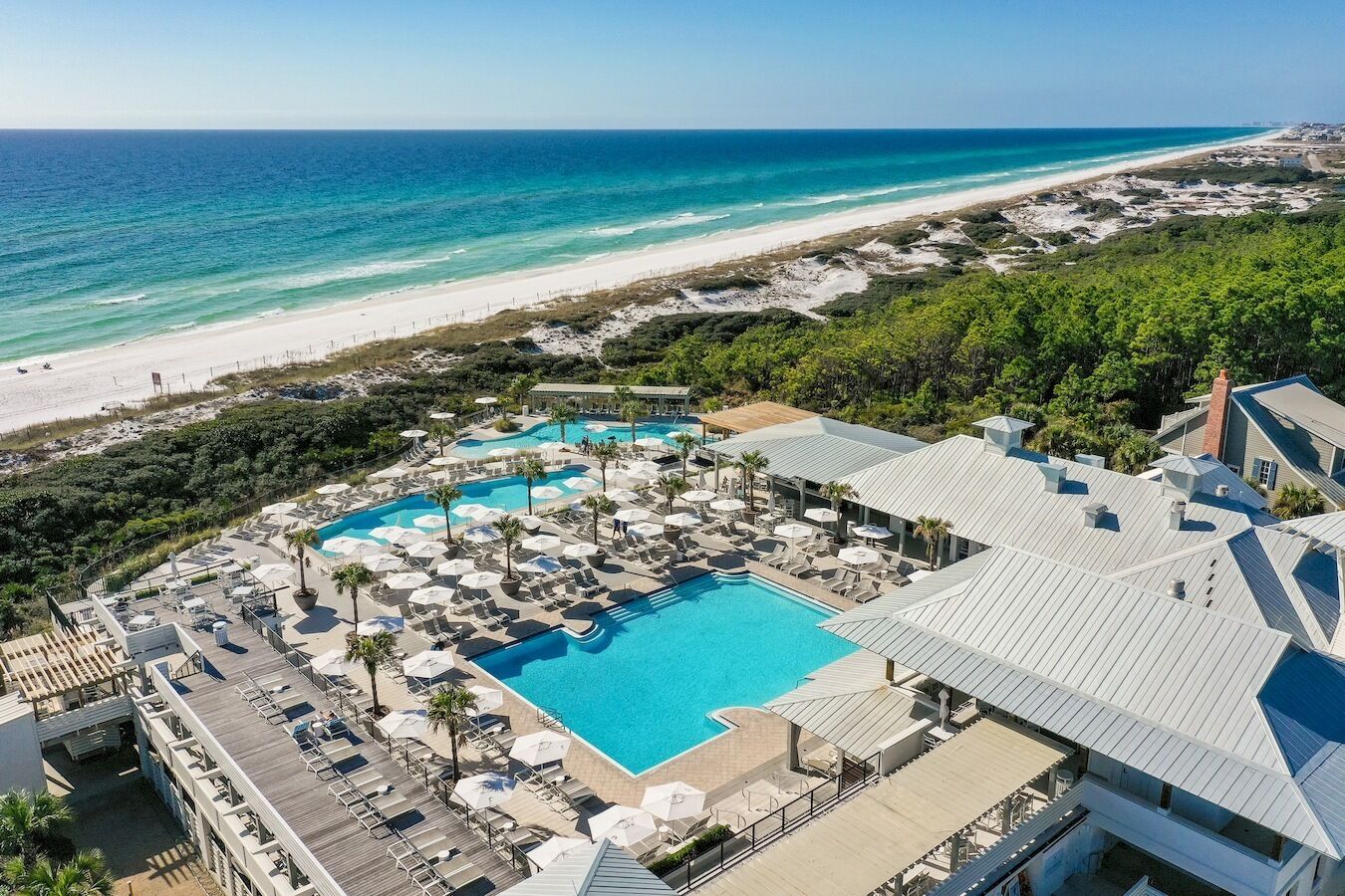Ein Resort mit großem Pool, Liegestühlen und Blick auf den Strand.