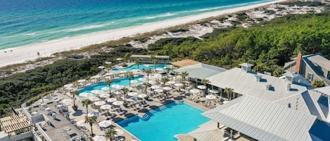 A resort with a large pool, lounge chairs, and a beach view.
