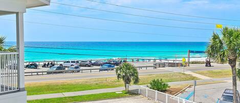Vista costera con playa, coches aparcados y cielo despejado.