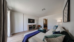 Ein modernes Hotelzimmer mit Bett, Fernseher, einer kleinen Ablage und Blick auf den Speisesaal.