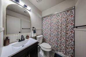 Une salle de bain avec un lavabo blanc, un robinet noir et des toilettes.