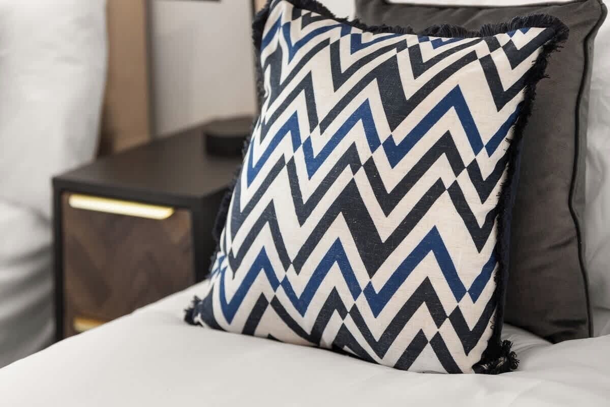 Un lit avec un oreiller à motifs, une table de chevet et une lampe.