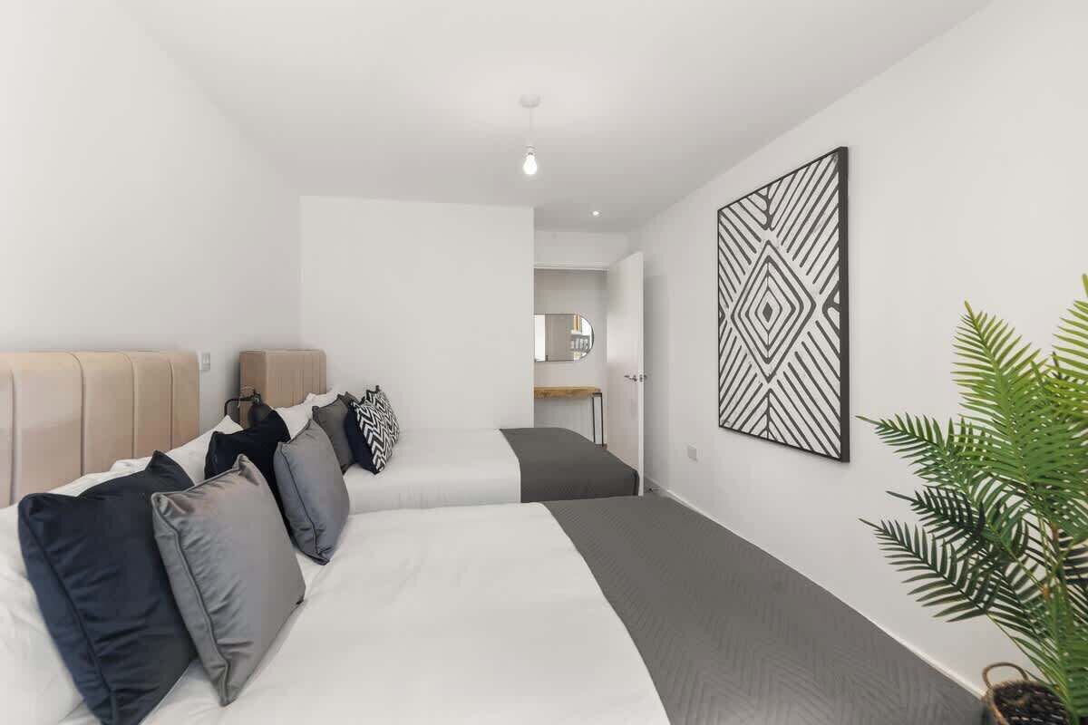 Een moderne hotelkamer met een groot bed, een hoofdbord, een kunstwerk aan de muur en een potplant.