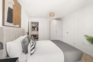 Un dormitorio moderno con una cama grande, una mesita de noche, una lámpara colgante y un armario.