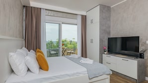 Un dormitorio moderno con cama, televisión y vistas al balcón.