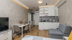 Un espacio habitable compacto con comedor, kitchenette y sofá.