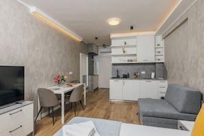 Un espacio habitable compacto con comedor, kitchenette y sofá.