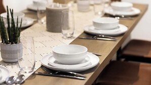 Une table à manger élégamment dressée, avec des assiettes, des bols, des couverts et un chandelier.