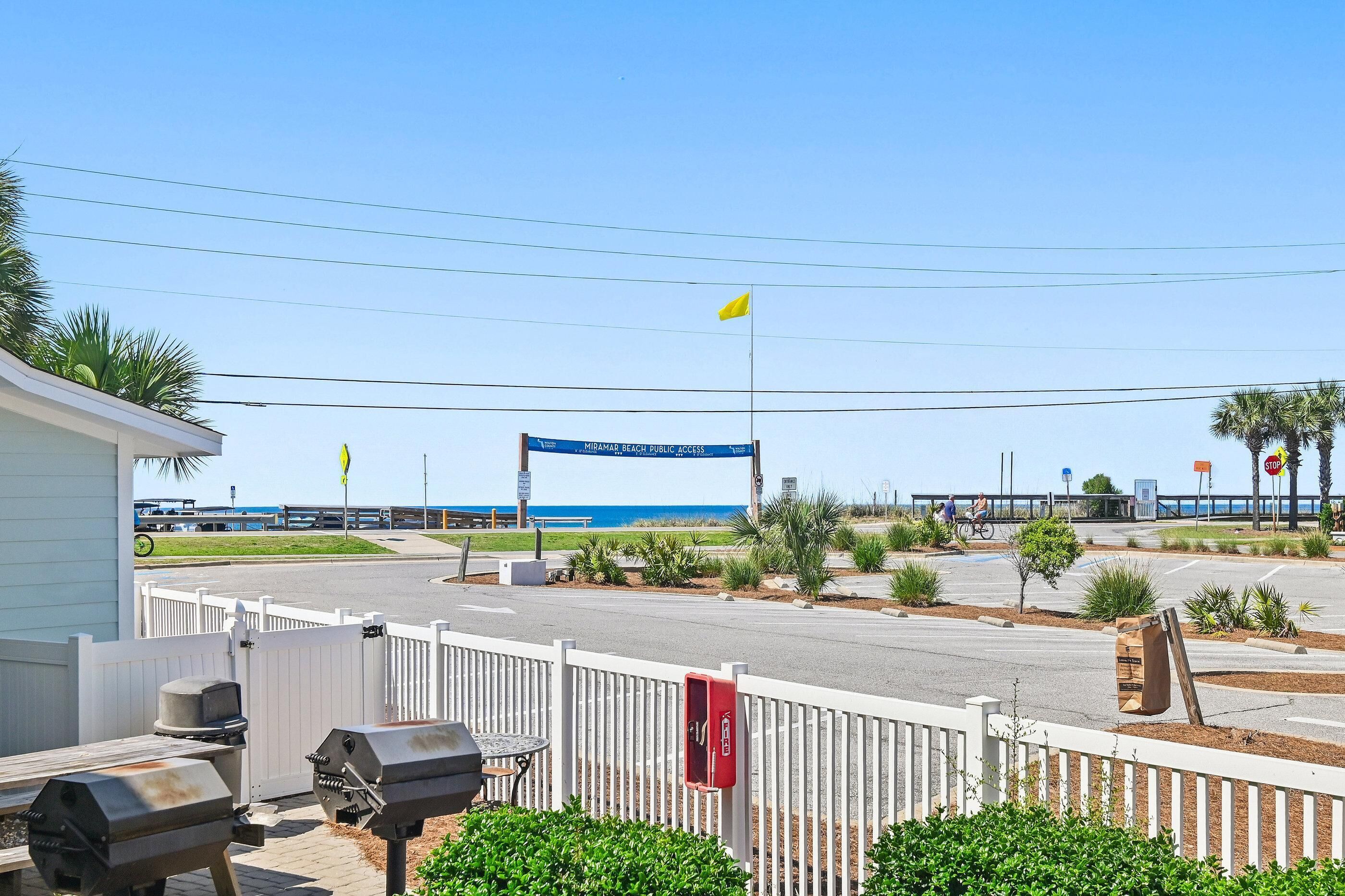 A street view with a blue sign, a white fence, and a grill area.