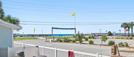 A street view with a blue sign, a white fence, and a grill area.