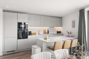 Una cocina moderna con electrodomésticos integrados, una isla central y una zona de comedor con sillas.
