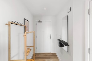 Un pasillo con un perchero de madera, una puerta y una repisa negra fijada a la pared.