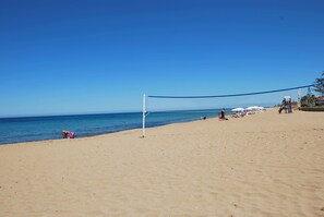 Una red de voleibol de playa en una arena con el océano al fondo.