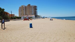 Una playa con un edificio grande, un bote de basura y un cielo despejado.