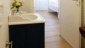 A narrow hallway with a white sink, a mirror, and a chandelier. - Dolce Conero Guest House (Camerano)