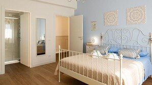 A bedroom with a white metal bed frame, a bedside table with a lamp, a mirror, and decorative wall art. - Dolce Conero Guest House (Camerano)