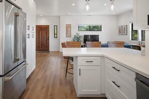 Eine moderne Küche mit weißen Schränken, einem Edelstahlkühlschrank und einem Holztisch.