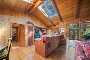 Ein Holzblockhaus mit einer Kochinsel, einem Essbereich und einem großen Fenster.