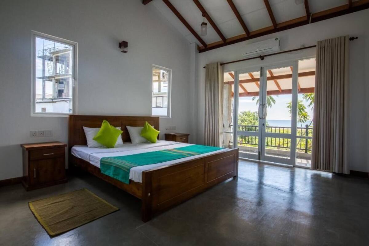 A bedroom with a wooden bed, a nightstand, a window, and a view of the outdoors.