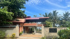 Un bâtiment avec un toit rouge, une enseigne indiquant « BLUE SANDS Beach Resort », et un chemin de terre menant à l’entrée.