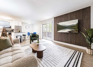 A modern living room with a sofa, a coffee table, and a dining area with chairs. - South Tampa 2BR | 2 Kings, Pool, Gym & Parking (Tampa)