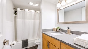 A bathroom with a shower, toilet, sink, and mirror. - South Tampa 2BR | 2 Kings, Pool, Gym & Parking (Tampa)