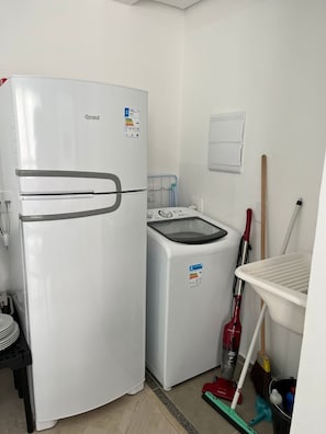 A compact kitchen with a white refrigerator, washing machine, and a small sink. - LK Centro 7 (Belo Horizonte)