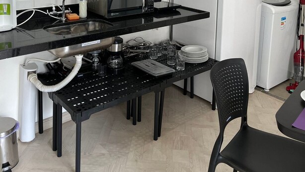 A compact kitchen with a microwave, toaster, sink, and a white refrigerator. - LK Centro 7 (Belo Horizonte)