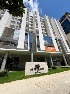 Un edificio moderno con un letrero que dice 'METROPOLIS EMCCAMP' y un letrero de 'ALUGA'.