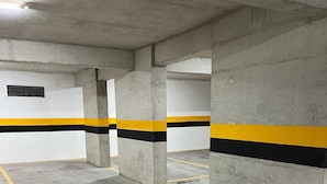 A parking garage with concrete pillars, yellow and black painted lines, and a clean, empty floor. - LK Centro 7 (Belo Horizonte)