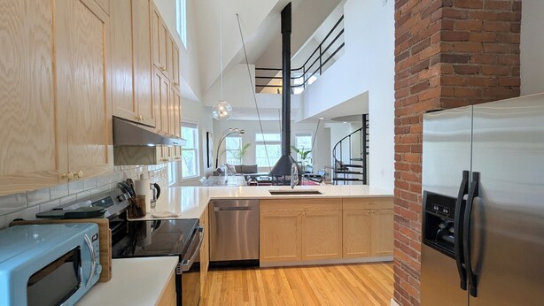 A modern kitchen with wooden cabinets, a stainless steel refrigerator, and a central island. - Modern Victorian Loft 4-bedroom duplex in Saint Paul's central Cathedral Hill (Saint Paul)
