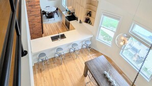 A modern kitchen with a central island, bar stools, and a dining table with a hanging light fixture. - Modern Victorian Loft 4-bedroom duplex in Saint Paul's central Cathedral Hill (Saint Paul)
