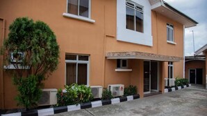 A two-story building with a flat roof, air conditioning units, and a paved entrance area.