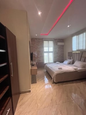 Un dormitorio con cama, escritorio, armario y ventana.