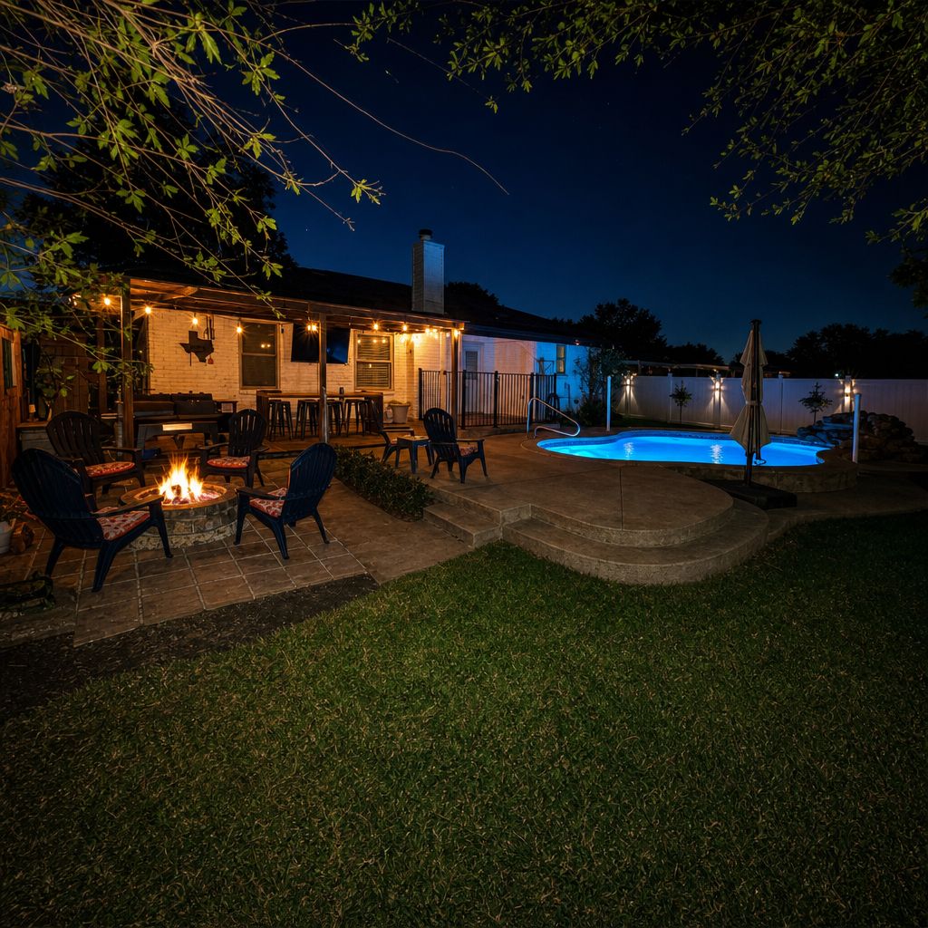 Patio trasero con piscina, mobiliario exterior y una chimenea.