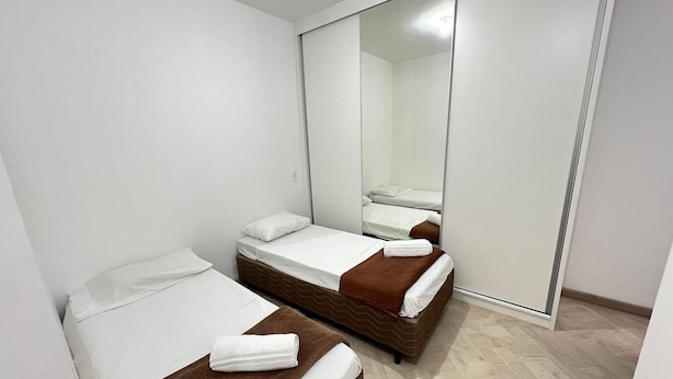 A hotel room with two beds, a large mirror, and a wardrobe. - LK Centro 8 (Belo Horizonte)