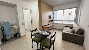 Un espacio habitable compacto con comedor, kitchenette y sofá.